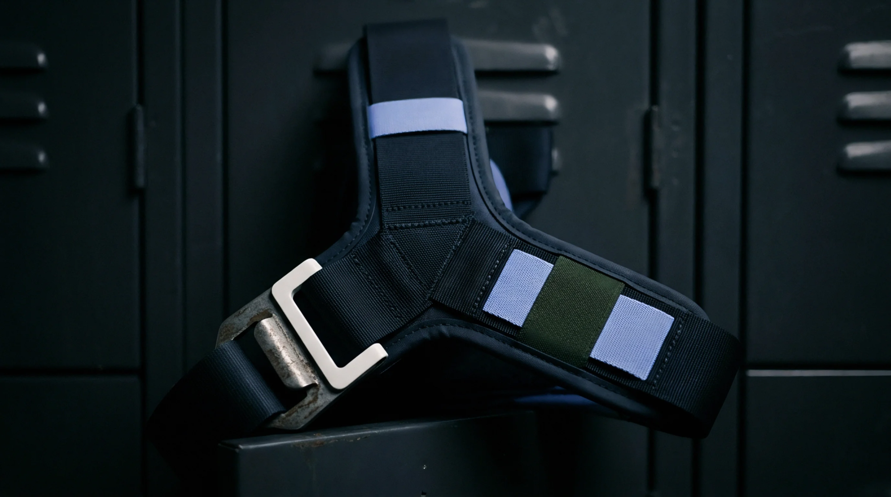 Industrial nylon webbing harness with metal fasteners rests on a dark steel surface suggesting industrial cargo securement protocols for transit and warehouse distribution systems.