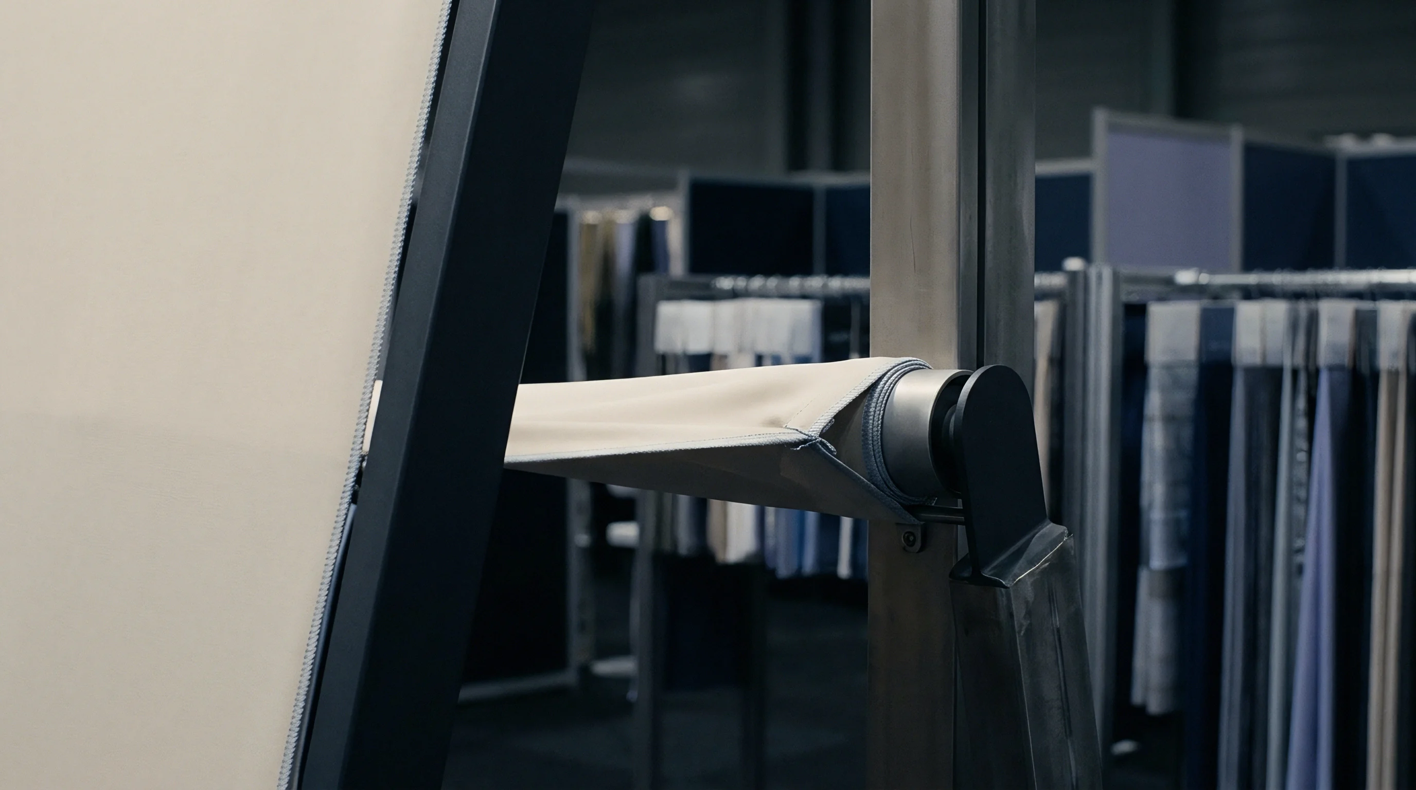 A light beige textile specimen attaches to a vertical metal frame using a zipper assembly within a commercial showroom or factory.