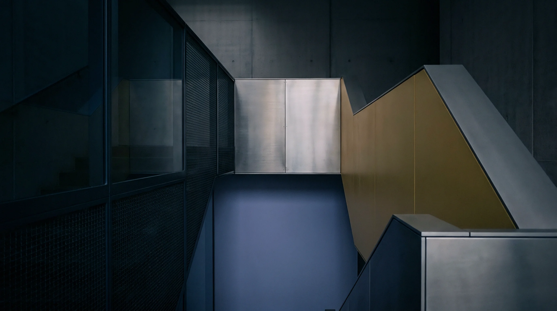 Metallic panels and yellow partitions define the vertical access routes within this industrial multi level facility featuring heavy steel mesh guards.