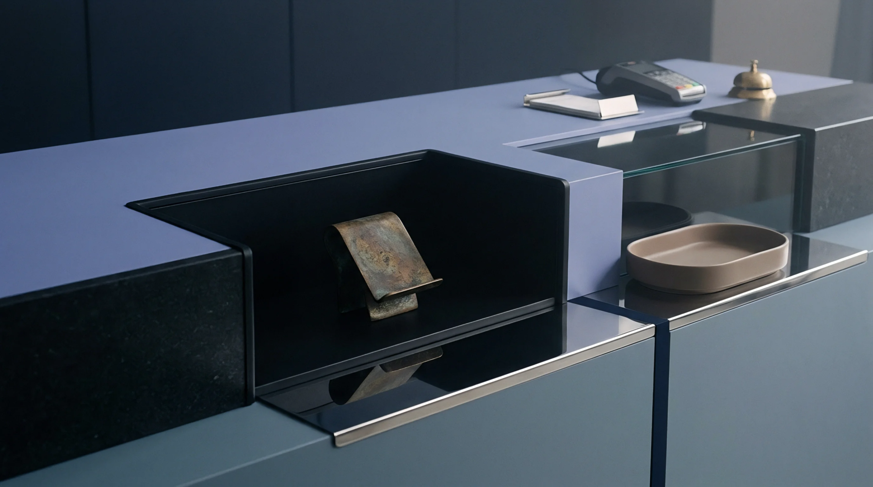 Matte blue and black composite service counter surfaces hold a brass bell, a payment terminal, and a glass display case.